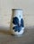 This elegant porcelain bud vase features a striking hand-painted blue anemone flower design against a crisp white...
