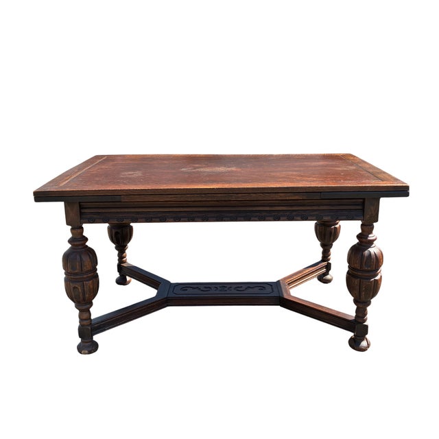 A substantial early 20th-century Jacobean Revival dining table crafted in richly grained oak and featuring an integrated...