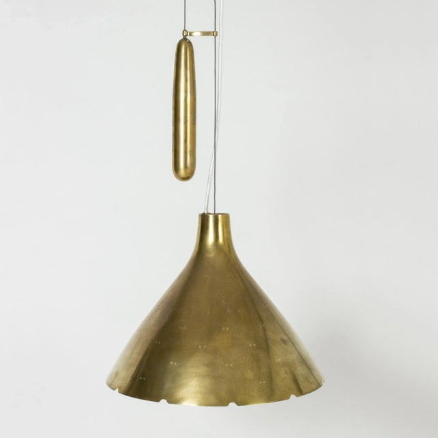 Beautiful brass ceiling lamp by Paavo Tynell, with a conical shade perforated with small holes and finished with a...