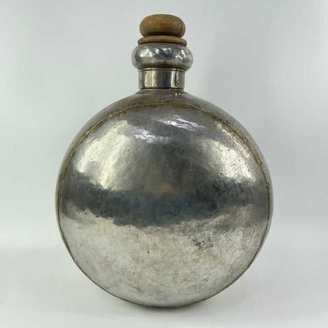 Vintage metal bottle from India with a rounded body. Made from polished metal with visible wear and repair marks. It has a...