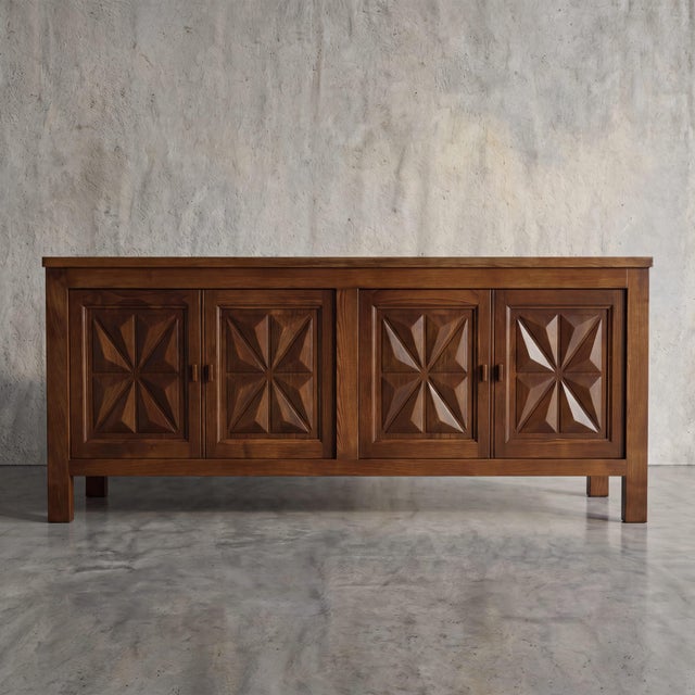 Bold, deeply carved geometric starburst motifs give this substantial four-door credenza an undeniable architectural...