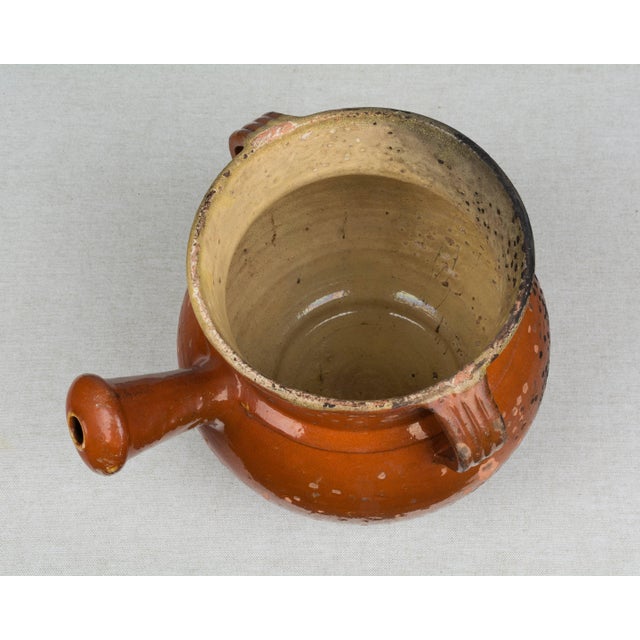 A 19th century French glazed terracotta Toupin pot with distressed, speckled terracotta glaze and yellow glazed interior....