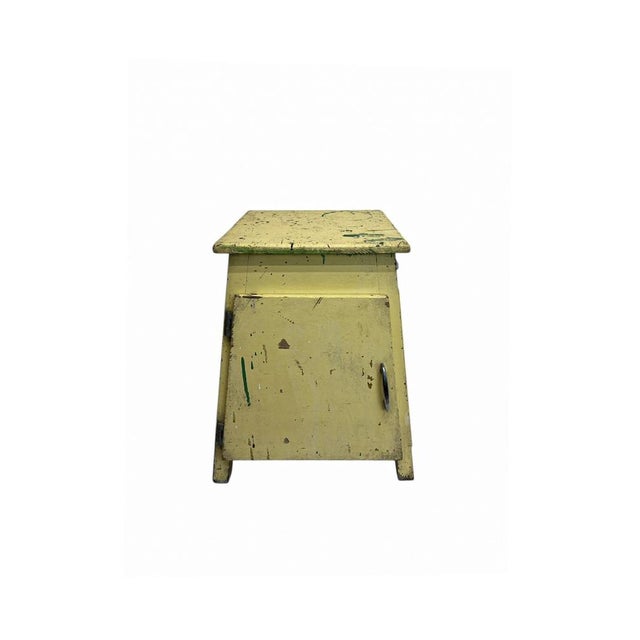 A small cabinet from the 1950s with a distinctive design featuring sloping sides. In its authentic yellow paint and with...