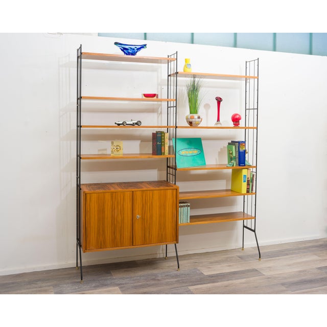 Delicate free-standing bookcase in walnut with black painted metal ladders. Design from the 60s. 9 shelves and a two-door...