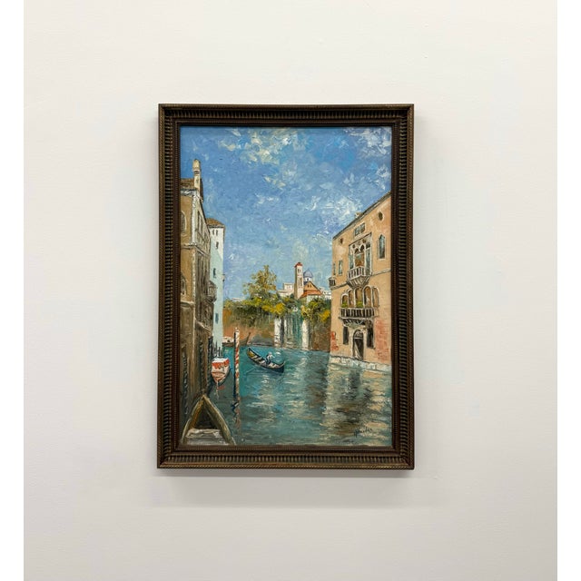 A vintage signed oil painting depicting a picturesque canal lined with historic architecture and a lone boat drifting...