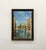 A vintage signed oil painting depicting a picturesque canal lined with historic architecture and a lone boat drifting...