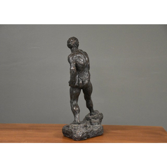 A brutalist style sculpture made of stone resin to simulate bronze. Titled Man With A Sling by Thomas Holland. Made in...
