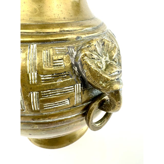 A striking antique Asian brass vase distinguished by its sculptural form and richly aged patina. The rounded body is...