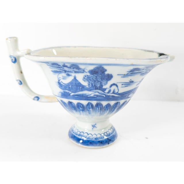 We are selling this Chinese Export Blue and White Canton helmet creamer with landscape decoration and libation cup form...