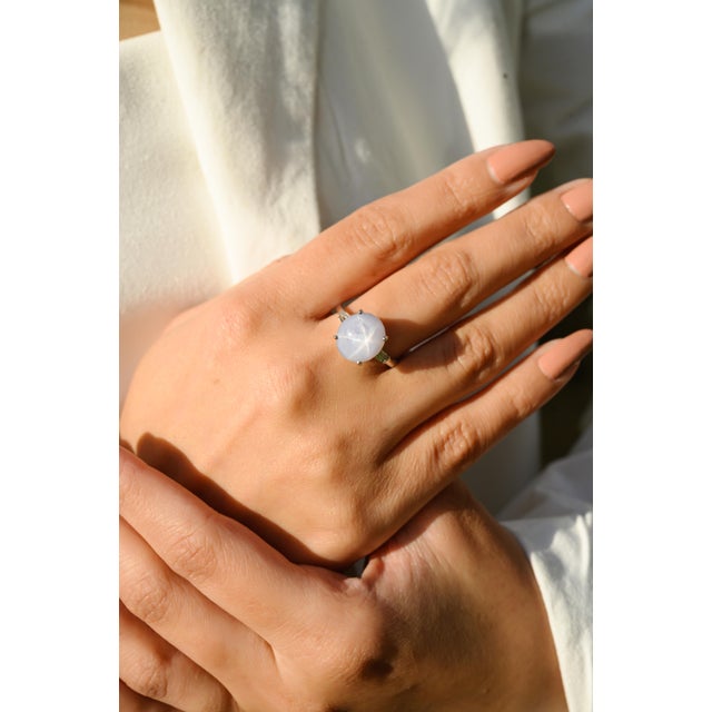 This striking cocktail ring showcases a mesmerizing natural star sapphire cabochon at the center weighs approximately 8.5...