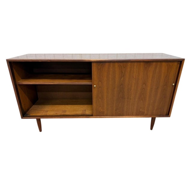 Elevate your space with this stunning 1960s American-made walnut sliding door cabinet, a true Mid-Century Modern classic....