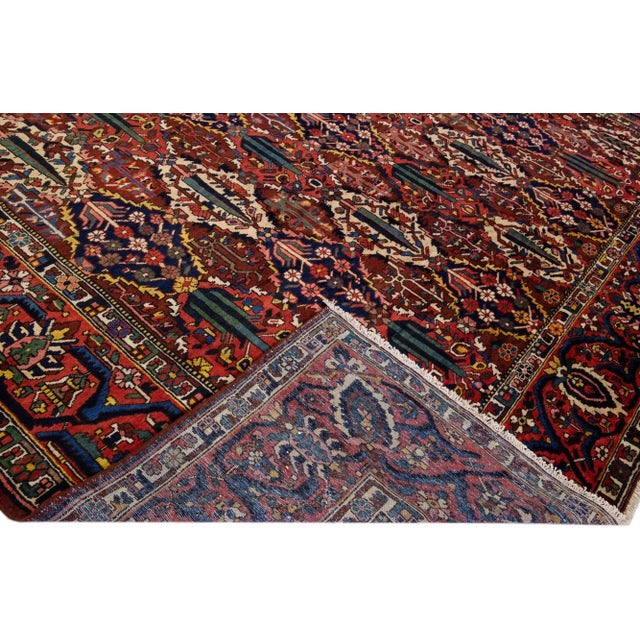 Beautiful Antique Bakhtiari hand-knotted wool rug with a red color field. This Persian piece has all-over multicolor...