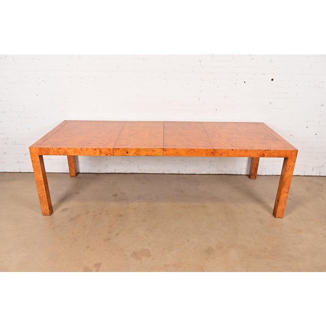 An exceptional Mid-Century Modern Parsons extension dining table in gorgeous book-matched burled olive wood In the manner...