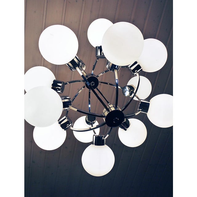 Elegant atomic structured pendant lamp with twelve white glass-globes on a chrome-plated frame. Chandelier illuminates...