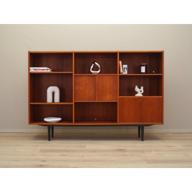 The bookcase was made in the 1970s, Danish production. The structure is covered with teak veneer. Legs made of solid wood...