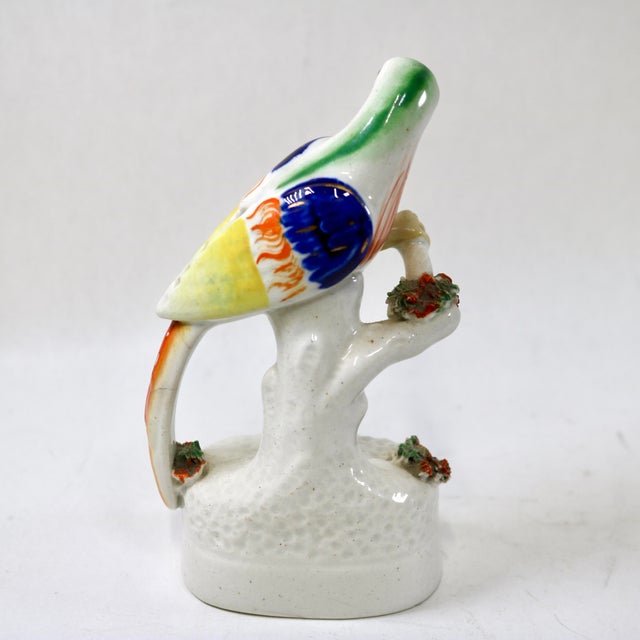 This charming mid-19th-century Staffordshire pottery figural quill holder depicts a vibrant parrot perched atop a mossy...