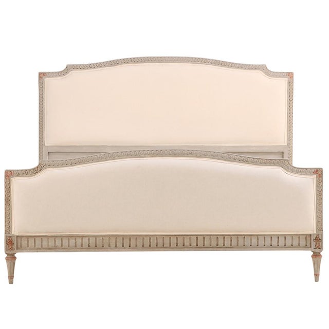 A refined Louis XVI style queen-size bed featuring a gracefully arched headboard and matching footboard, each with crisply...