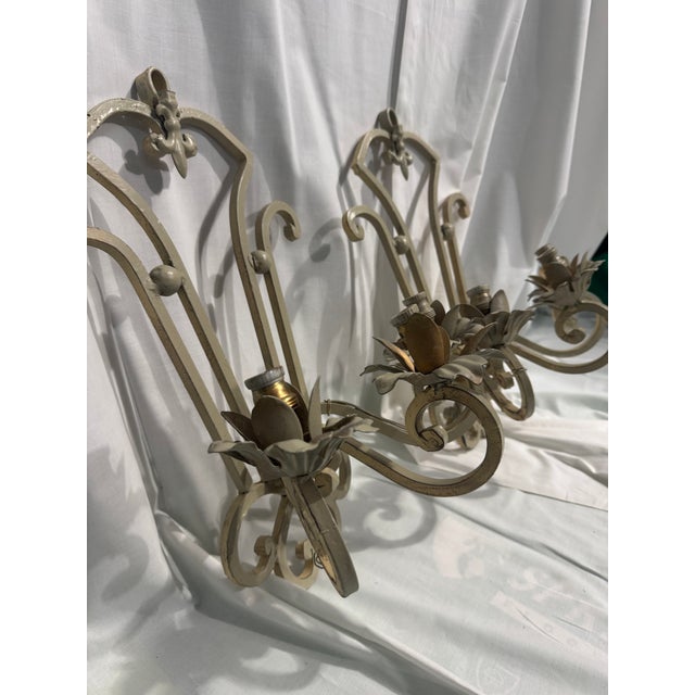 Vintage French Regency style wrought iron wall sconces with a distressed beige finish and sculpted floral candle holders