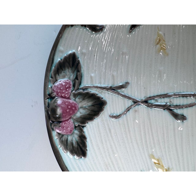 Offering a small plate designed with two sets of strawberries and leaves and knotted bows along the edges. The antique...