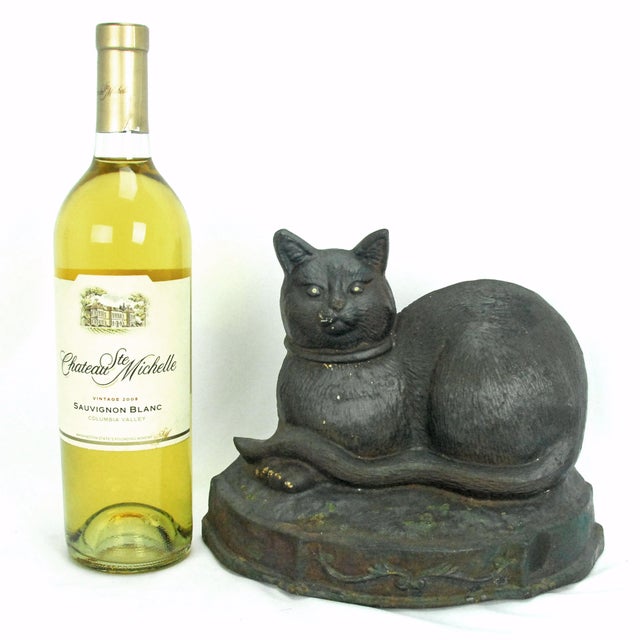 A large and substantial antique cast-iron doorstop featuring a cat peacefully resting on an ornate raised platform. Heavy...