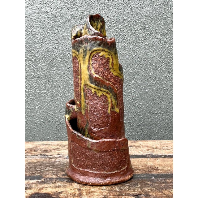 This vintage abstract pottery vase presents a boldly sculptural silhouette, its dynamic, tiered form rising through...