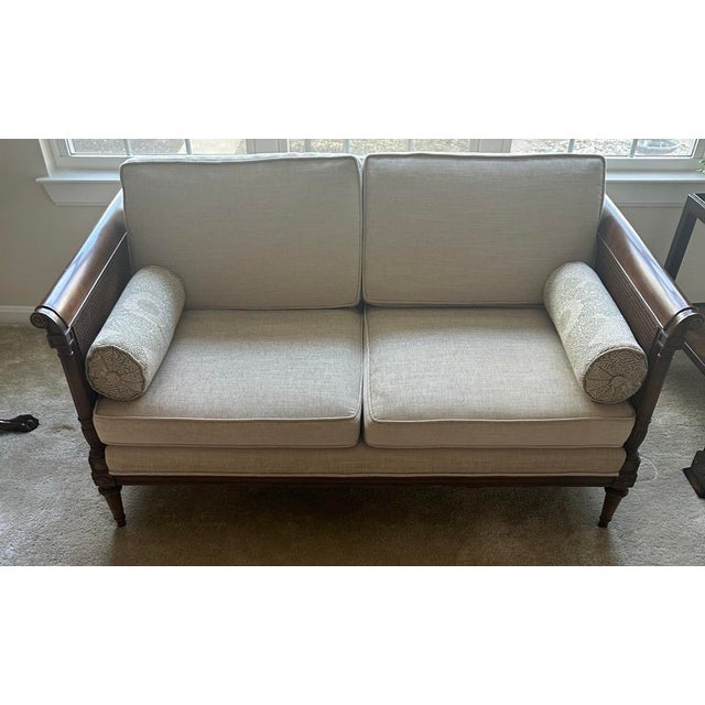 Vintage cane settee with classic, tailored lines. Professionally reupholstered in a neutral herringbone fabric, with two...