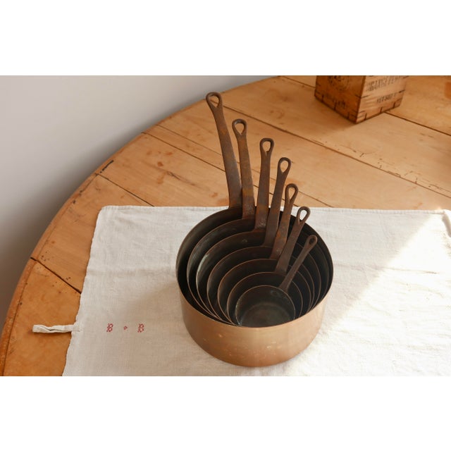 Set of 7 antique French copper nesting saucepans with riveted iron handles and a beautiful, authentic patina. Their warm...