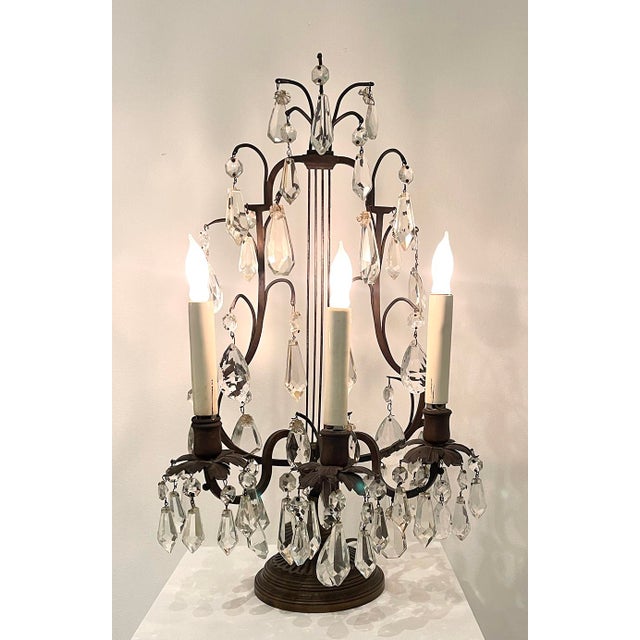 A finely composed pair of crystal girandole table lamps, distinguished by their sculptural bronze-tone frameworks and...