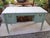 A vanity table from the 1960s, with a hinged center panel to which a mirror was probably once attached. The compartments...
