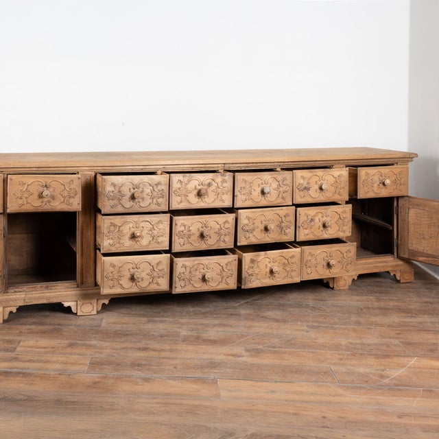 Visually striking French sideboard with decorative carved accents and flourishes throughout the 14 drawers and two cabinet...