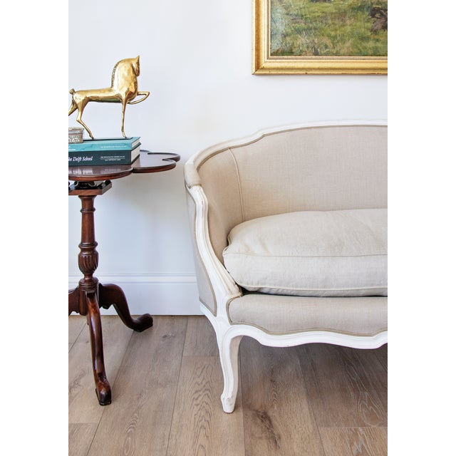An elegant Louis XV-style painted canapé featuring a gracefully shaped serpentine frame, flowing cabriole legs, and a...