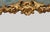 A dramatic vintage wall mirror featuring an elegant frameless silhouette accented with elaborate gilt Rococo-style floral...