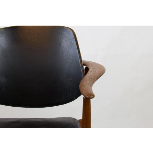 This teak armchair by Arne Hovmand- Olsen features black leather upholstery.