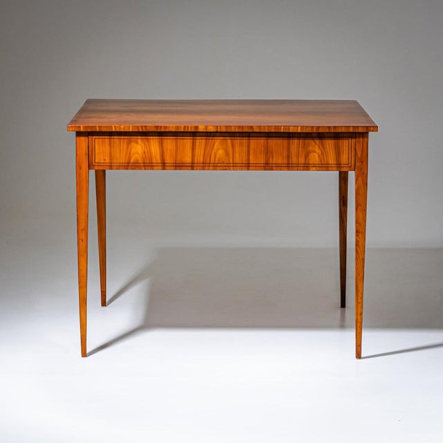 Rectangular Biedermeier table raised on tapered square legs, featuring fine string inlay framing the apron and tabletop. A...