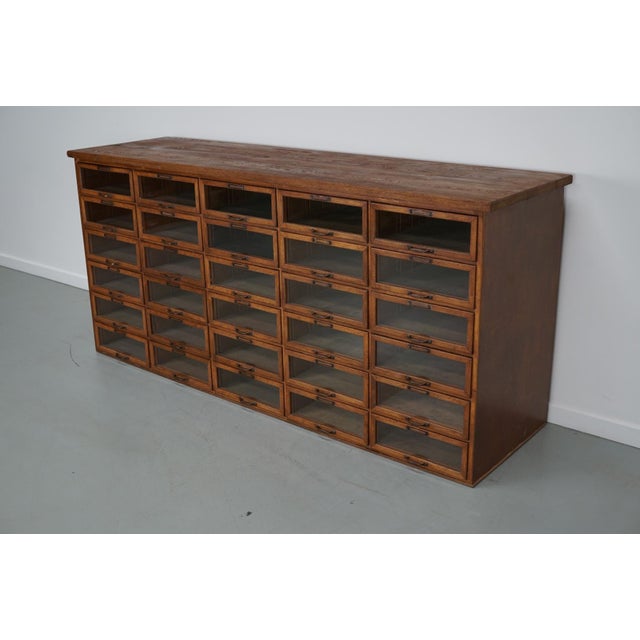 This haberdashery cabinet was produced during the 1930s in the Netherlands. It features 30 drawers in oak with glass...