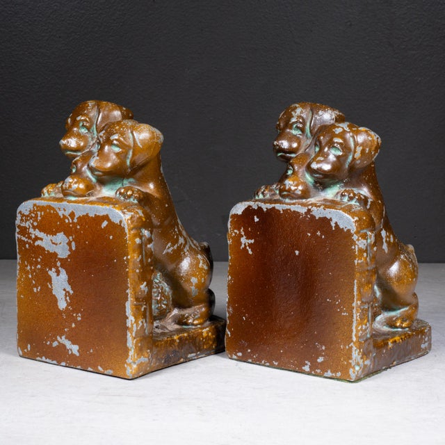 ABOUT A pair of Art Deco cast metal bookends, commonly known as the "Take A Peek With Me" model. They feature an...