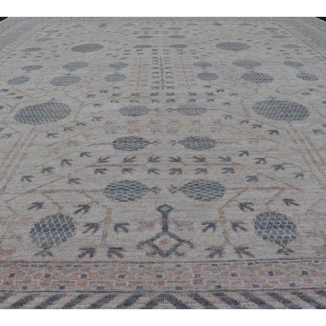 This modern Khotan features a modern muted array of teal, cream, taupe. The background is a beautifully blended cream,...