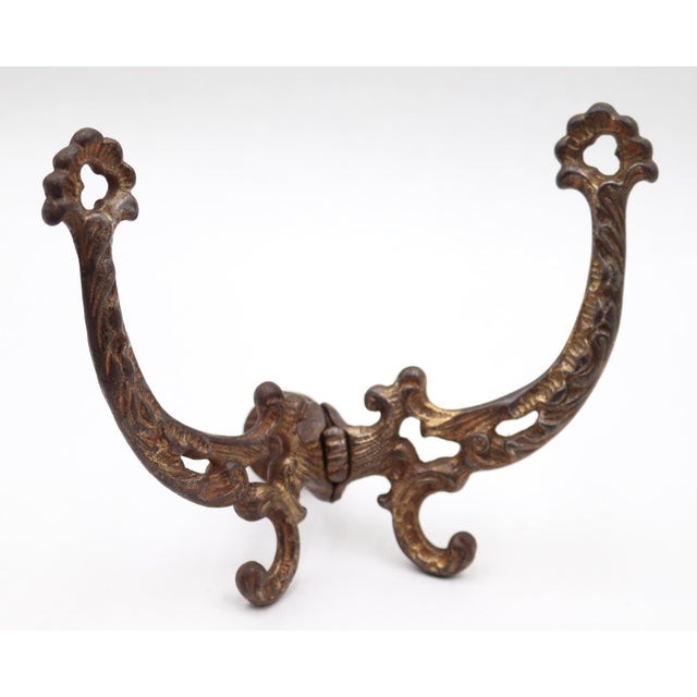 Antique Victorian style hall tree hook made of cast iron with brass plating. There is a screw attached to the back with a...