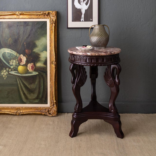 This Empire-style side table features a pink marble top and three legs carved into the shape of swans. The table base is a...