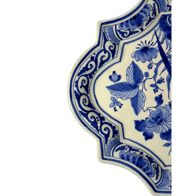 A vintage hand-painted royal delft wall plaque by de porceleyne fles, dating to 1980. The plaque has a shaped outline and...