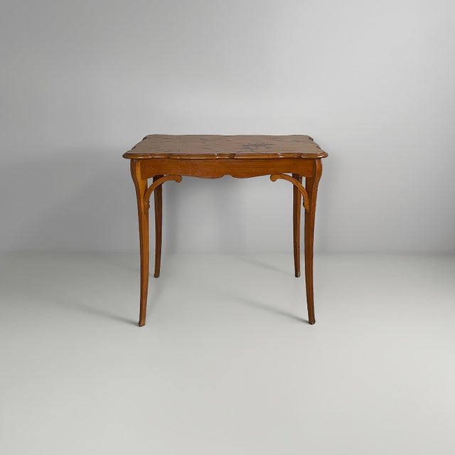 French coffee table in wood with undulating edges. The top features floral decorations and naturalistic motifs inlaid in...