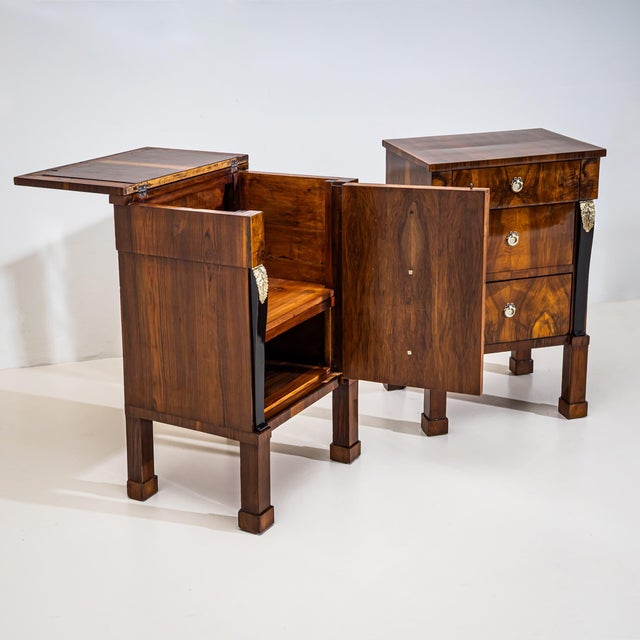 Pair of Empire bedside cabinets veneered in walnut and raised on tall square legs with block feet. The sides are decorated...