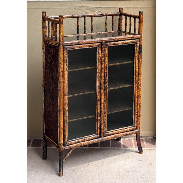 A handsome English bamboo bookcase cabinet from the Aesthetic Movement period, featuring a decorative gallery top of...