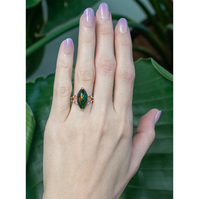 A captivating 4.1 carat black opal glows with rich, shifting colors, beautifully complemented by earth-mined diamond...