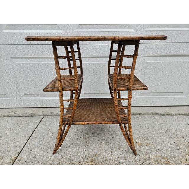 This antique burnt bamboo and wood three-tiered side table has unique arched supports with a split middle tier. The lower...