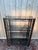 A 1970s design-style shelf with a tubular brass frame and four tinted smoked glass shelves. the structure consists of...