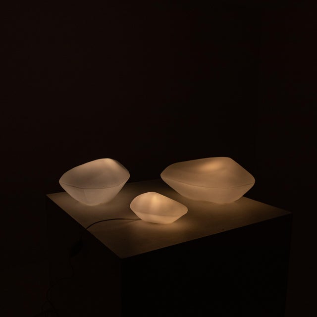 Set of three Stone of Glass lamps, produced by Oluce in the 1970s and 1980s. The glass frame features a milky white...