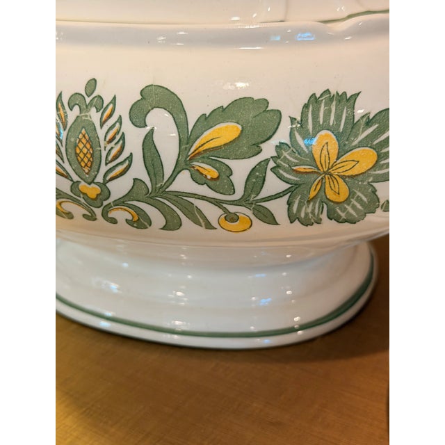Elegant vintage covered soup tureen featuring a romantic green and golden yellow floral motif on a creamy white ground....