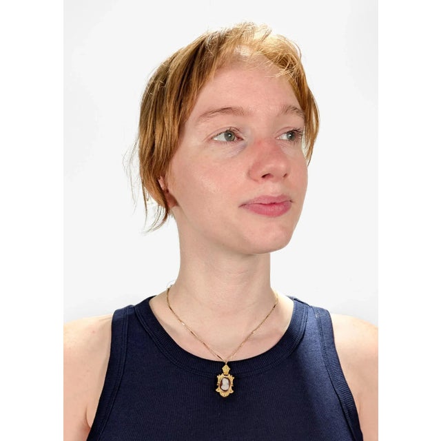 A fine antique Victorian pendant for a necklace. In 14 karat gold. Centered on a salmon and white carved agate or...