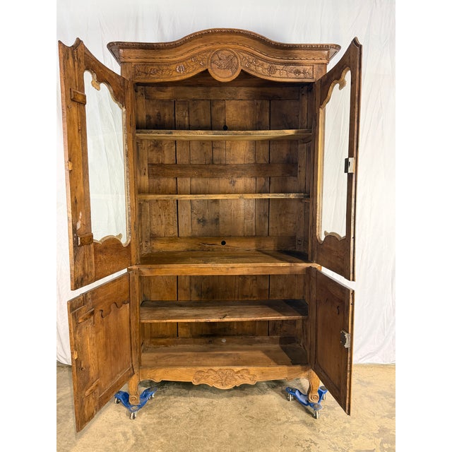 Antique 1840'sornately carved oak French bookcase, featuring two glass-paneled upper doors and two solid lower doors....